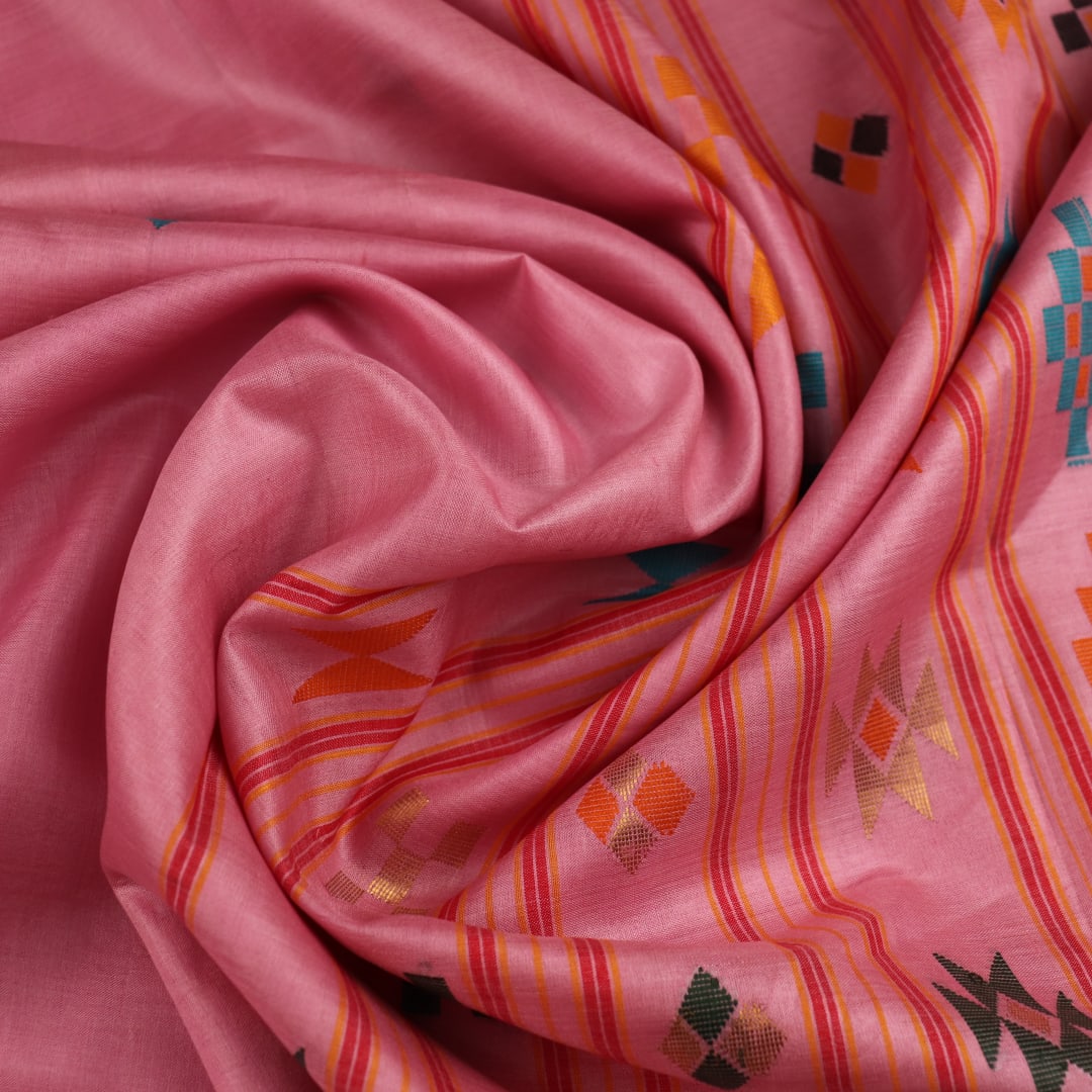 Close-up view of the smooth, textured tussar silk fabric in a delicate pink hue, showcasing the intricate butta pattern.