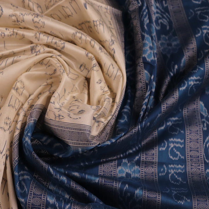 Close-up detail of the cream-colored silk fabric texture with blue motifs in Sambalpuri saree