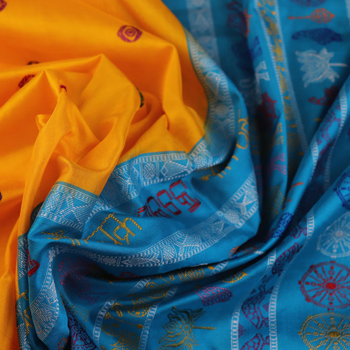 Close-up of the yellow Bomkai silk saree fabric texture, revealing its intricate weave and butta pattern.