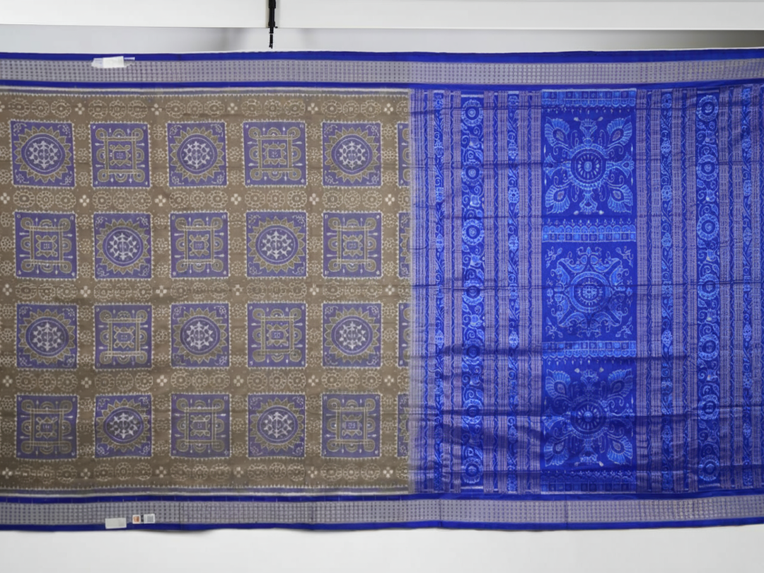 Extreme close-up of the grey and blue Sambalpuri silk saree fabric, revealing its rich texture and intricate weave.