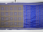 Extreme close-up of the grey and blue Sambalpuri silk saree fabric, revealing its rich texture and intricate weave.