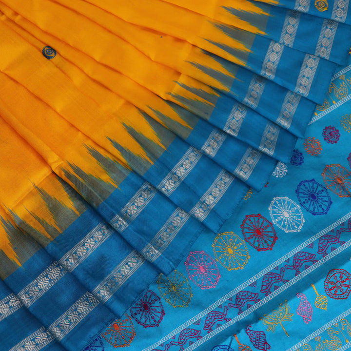 Close-up of the yellow Bomkai silk saree fabric texture, revealing its intricate weave and butta pattern.