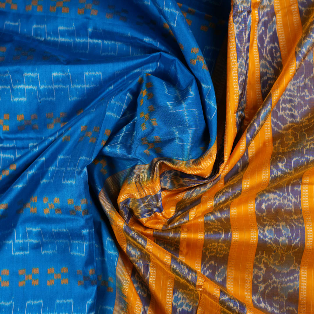 Close-up of the luxurious Sambalpuri silk fabric, highlighting its rich texture and handloom weave in blue and yellow.