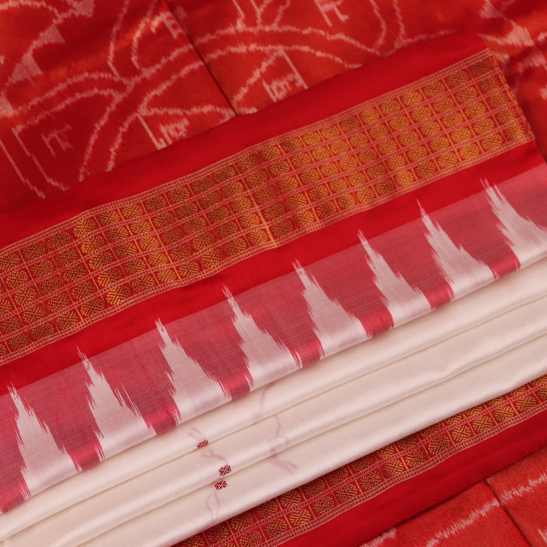 Close-up of white and red silk Bomkai saree fabric texture with butta pattern.
