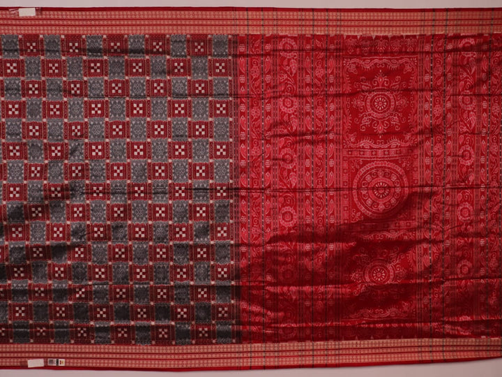 Close-up of grey Sambalpuri silk saree fabric showing intricate woven motifs and texture.