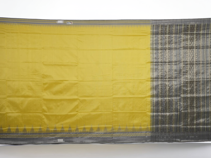 Close-up of the luxurious yellow Sambalpuri silk fabric, showing its fine weave and texture.