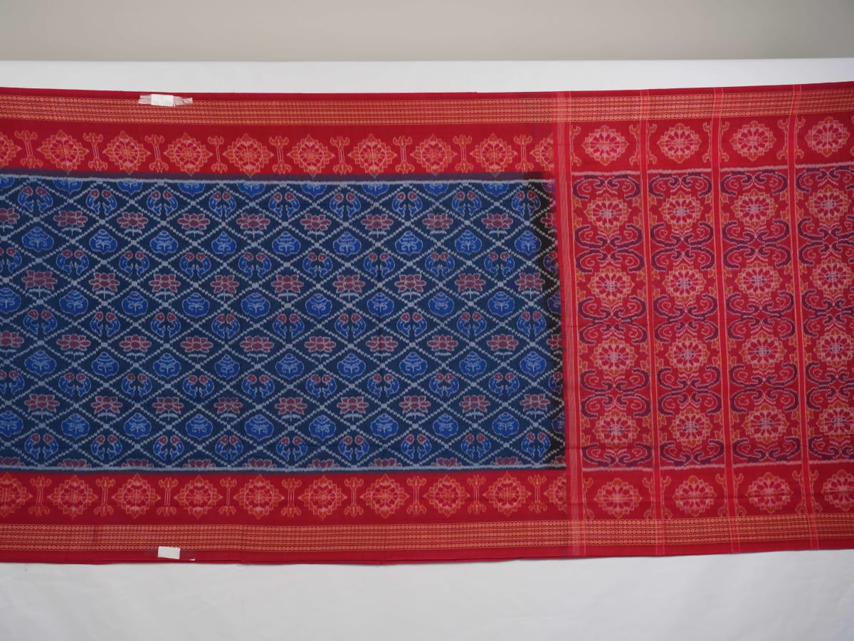 Full flat lay view of a blue and red Sambalpuri cotton saree showcasing the entire body and pallu design.