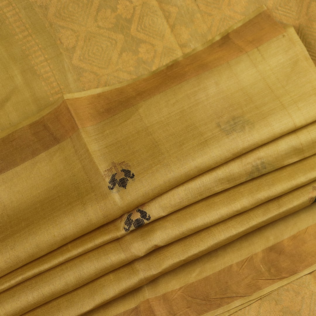 Close-up of yellow Tussar silk saree fabric with intricate butta patterns