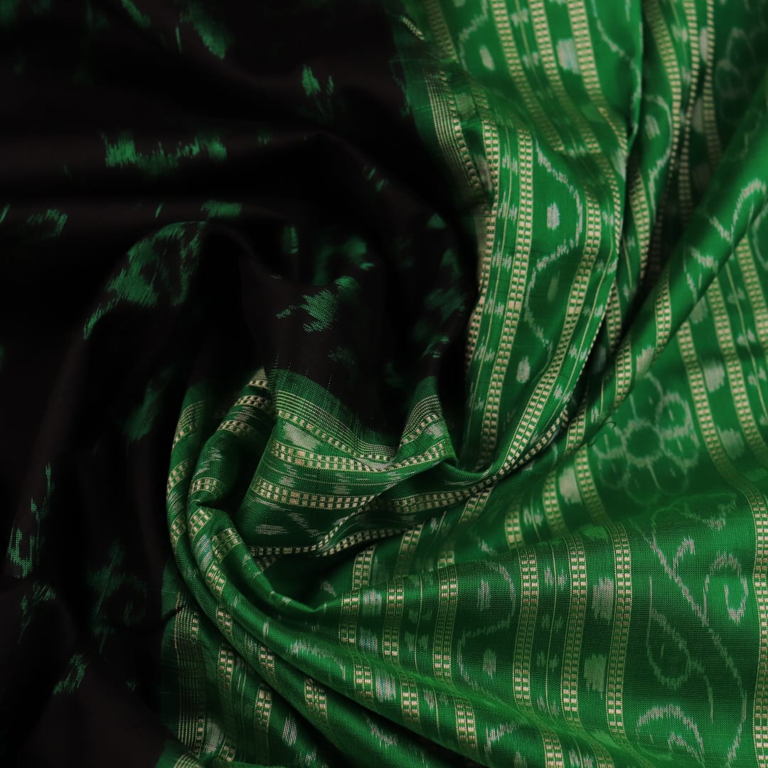 Close-up showcase of the exquisite silk texture with intricate motifs in a black and green Sambalpuri saree.