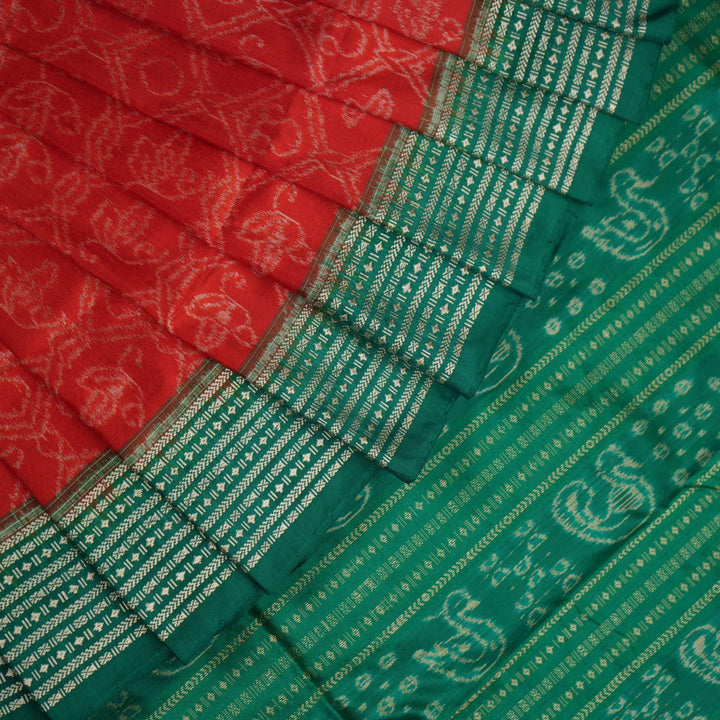 Extreme close-up of the rich orange Sambalpuri silk fabric, highlighting its intricate handloom weave texture.