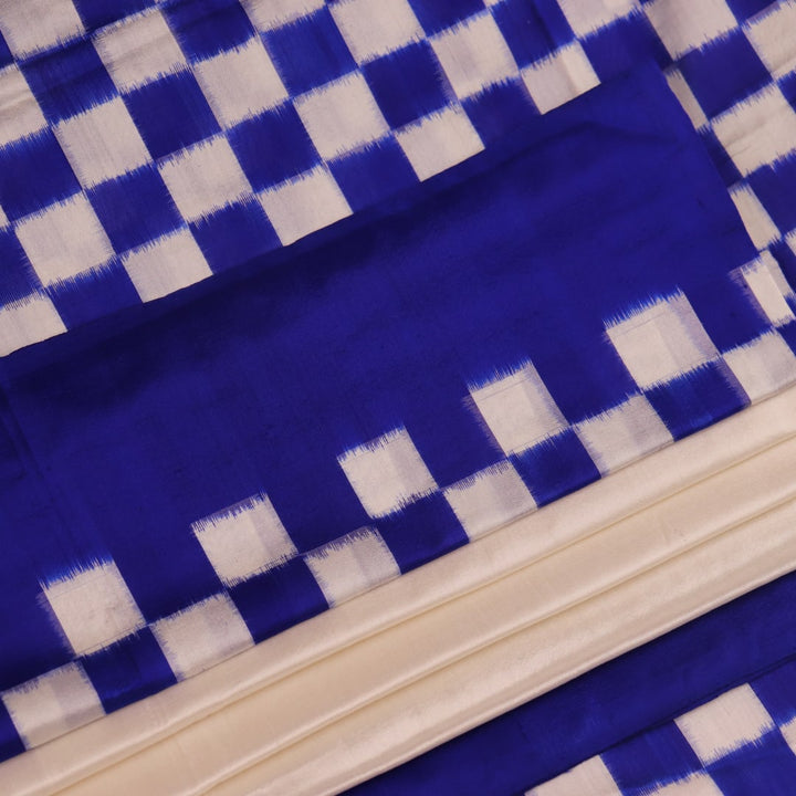 Close-up of the intricate Pasapalli pattern woven on a luxurious white silk Sambalpuri saree with blue accents.