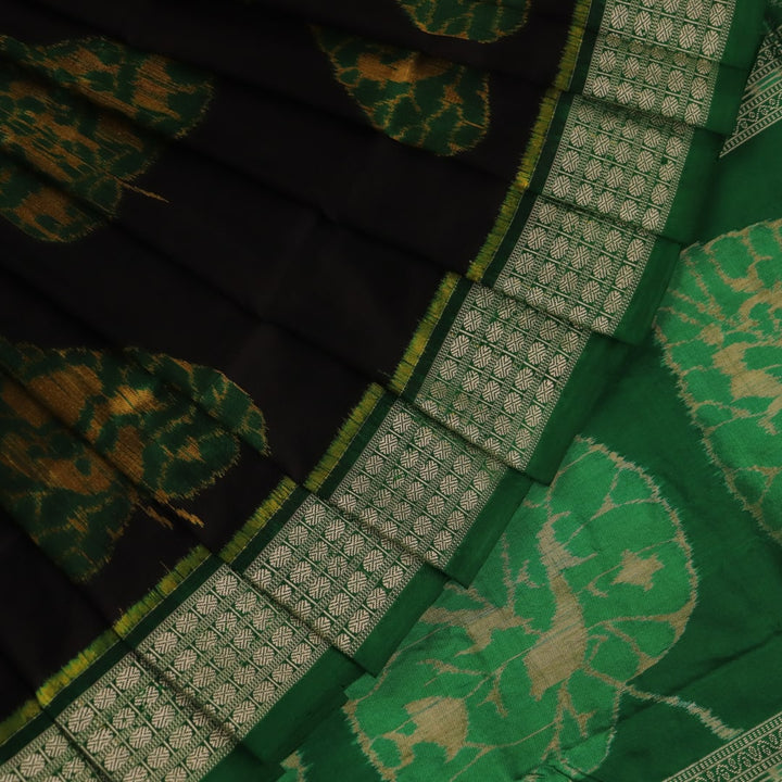 Close-up of the finely textured silk fabric in black, adorned with intricate Sambalpuri motifs in green