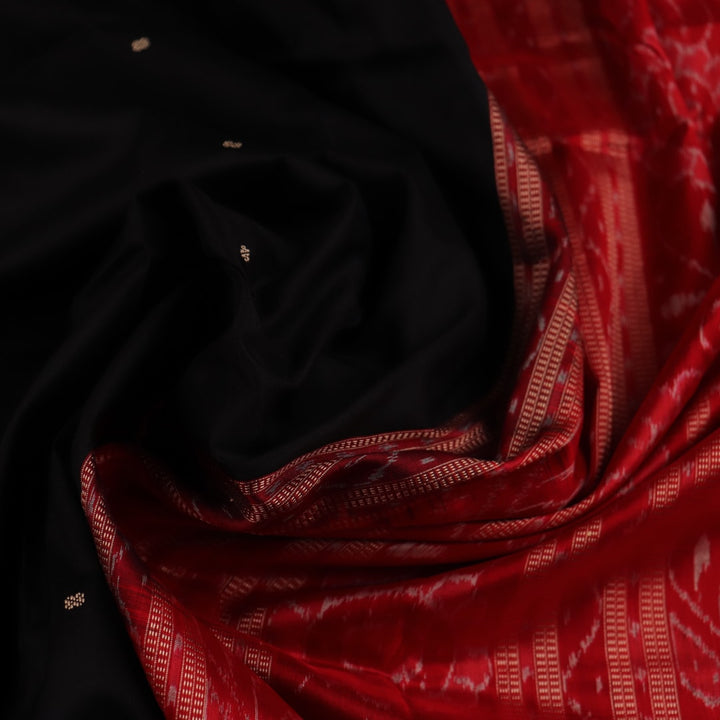 Close-up of black and red silk saree fabric with intricate Sambalpuri motifs