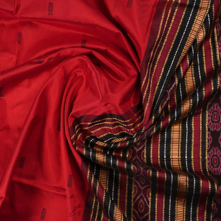 Detailed view of hand-woven silk fabric texture and butta patterns on a red Sambalpuri saree.