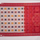 Model wearing a white and red Sambalpuri cotton saree with traditional motifs, styled for an elegant look.