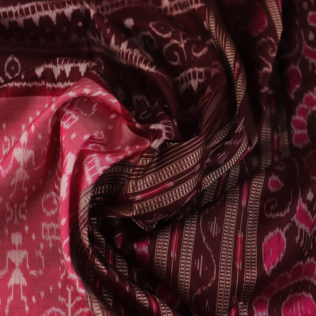 Close-up of peach and maroon Sambalpuri silk saree fabric showing intricate handloom texture and motifs.