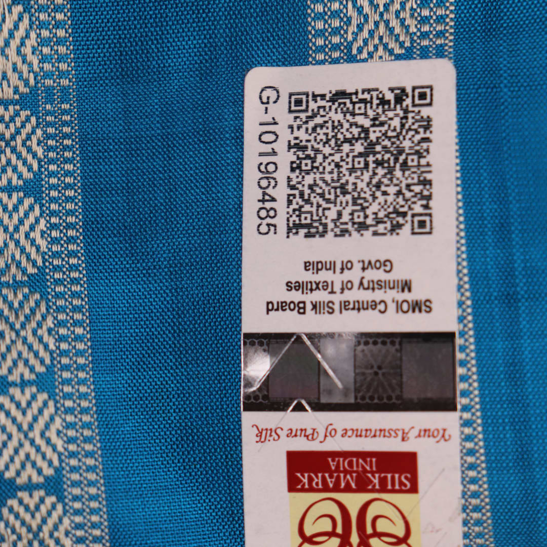Close-up of the yellow Bomkai silk saree fabric texture, revealing its intricate weave and butta pattern.