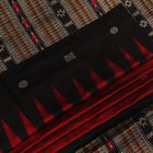 Close-up texture of handwoven Bomkai silk saree fabric: maroon and black threads forming butta pattern.
