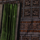 Close-up view of the silken texture of the Sambalpuri silk saree, showcasing green and black woven motifs.