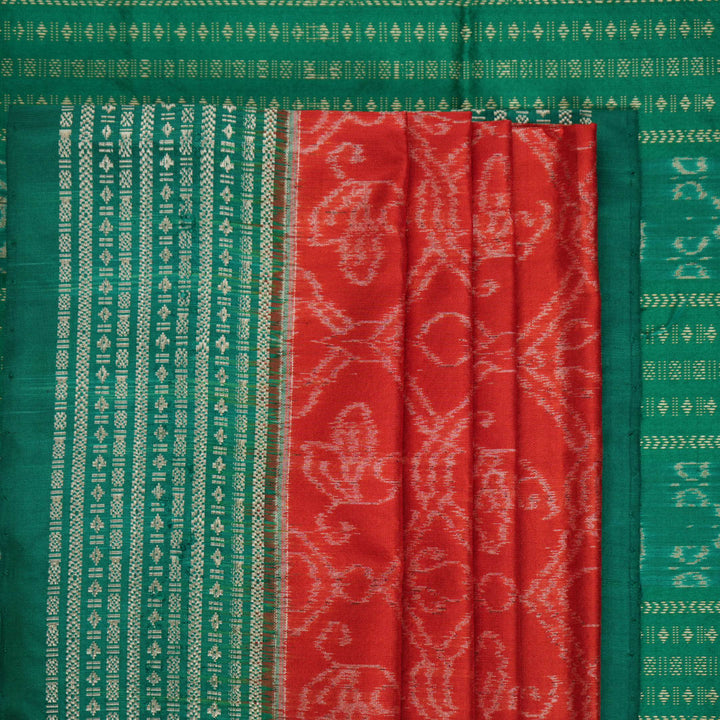 Extreme close-up of the rich orange Sambalpuri silk fabric, highlighting its intricate handloom weave texture.