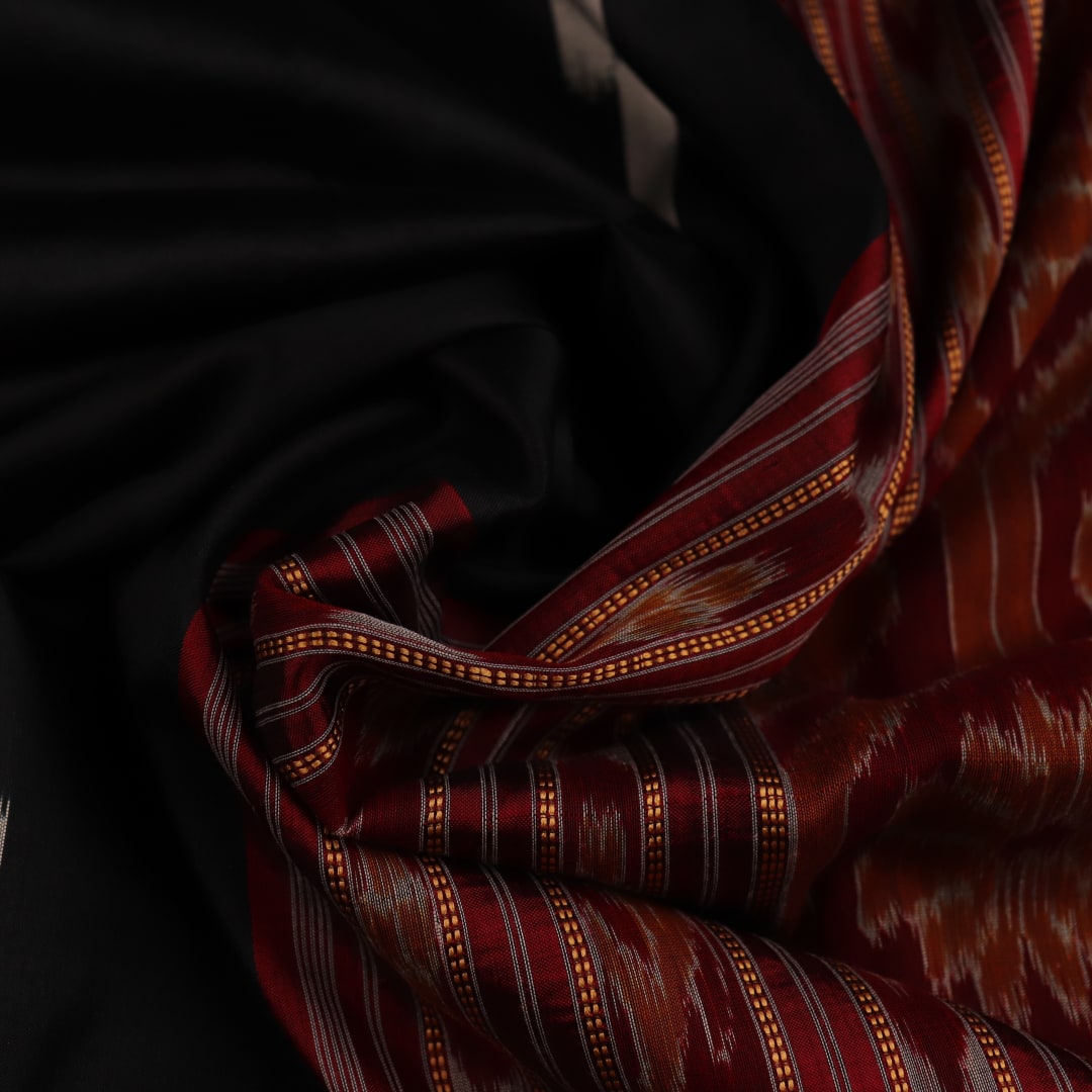 Khandua silk saree in black with red motifs, draped in a traditional style