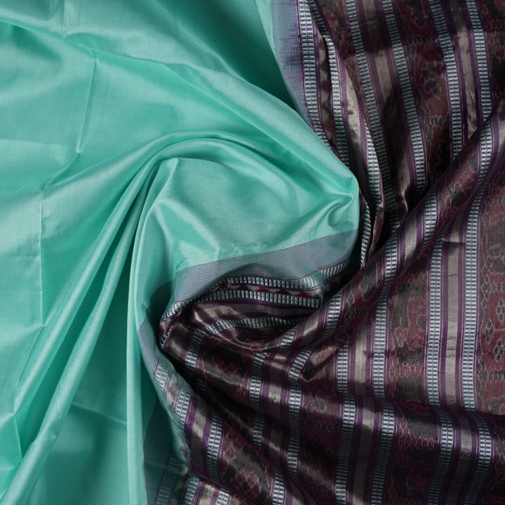 Ultra close-up of the luxurious green Sambalpuri handloom silk weave, highlighting its smooth texture.