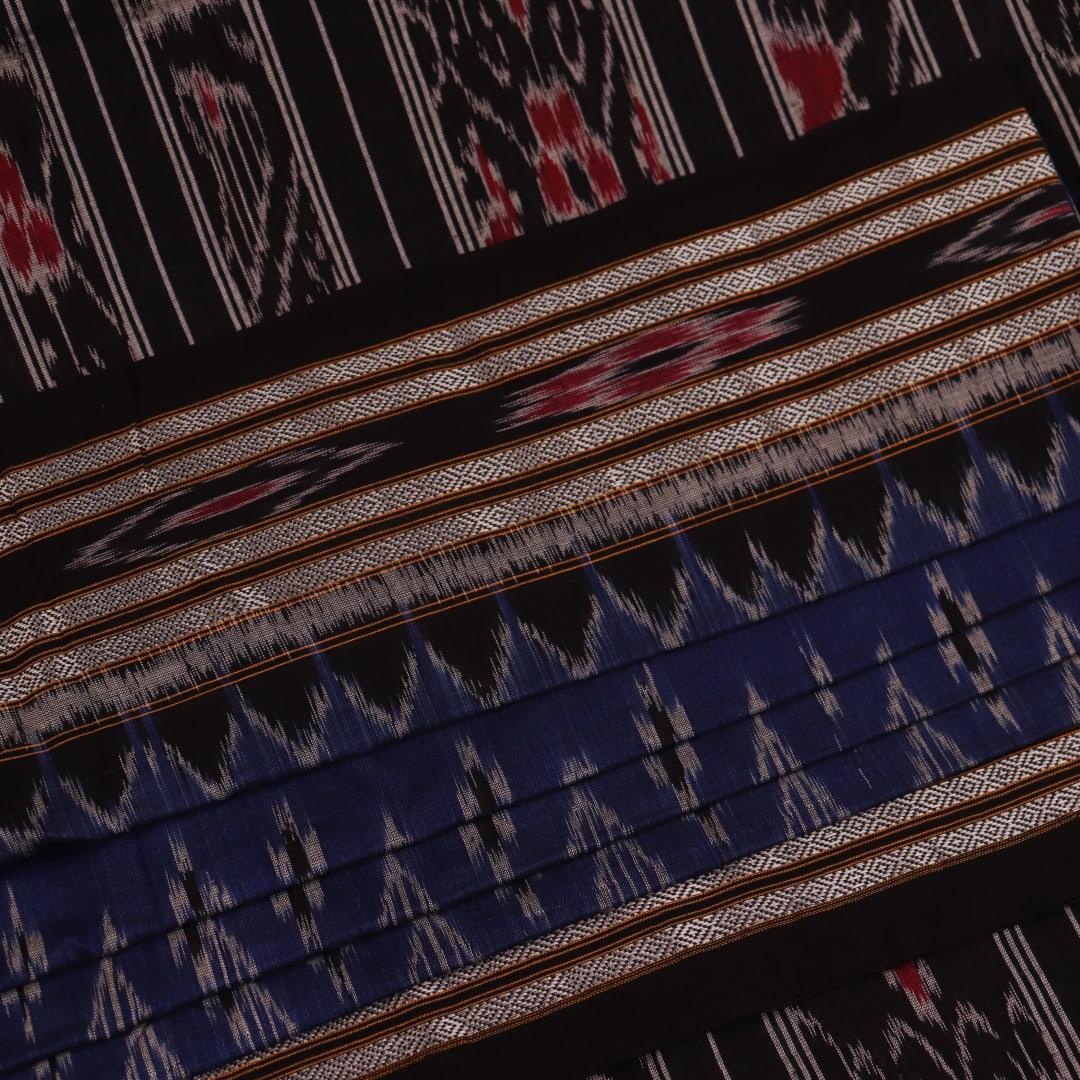 A person wearing a vibrant blue cotton Sambalpuri saree with black motifs, styled in a traditional drape.