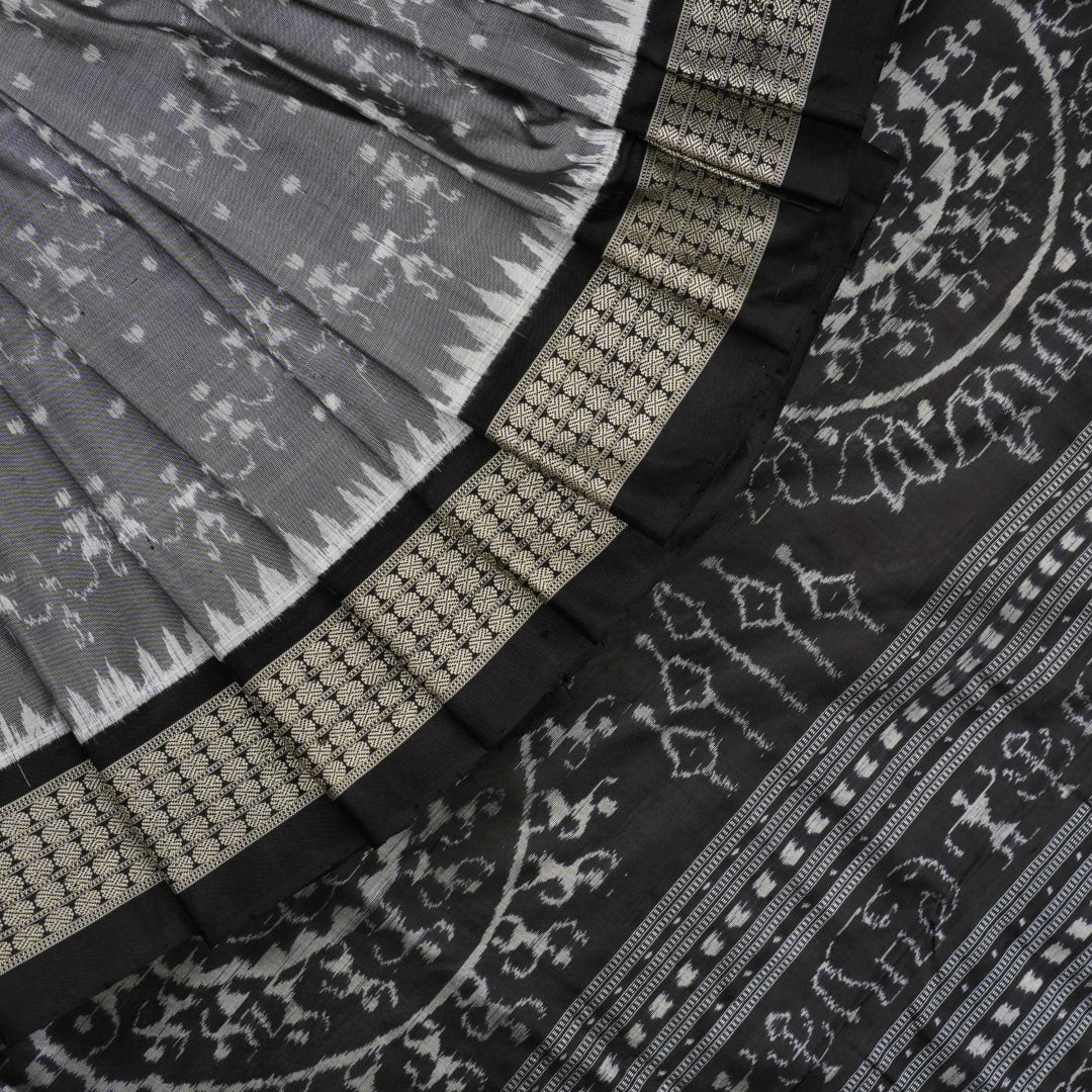 Close-up of grey & black Sambalpuri silk saree fabric, highlighting its rich texture and weave.