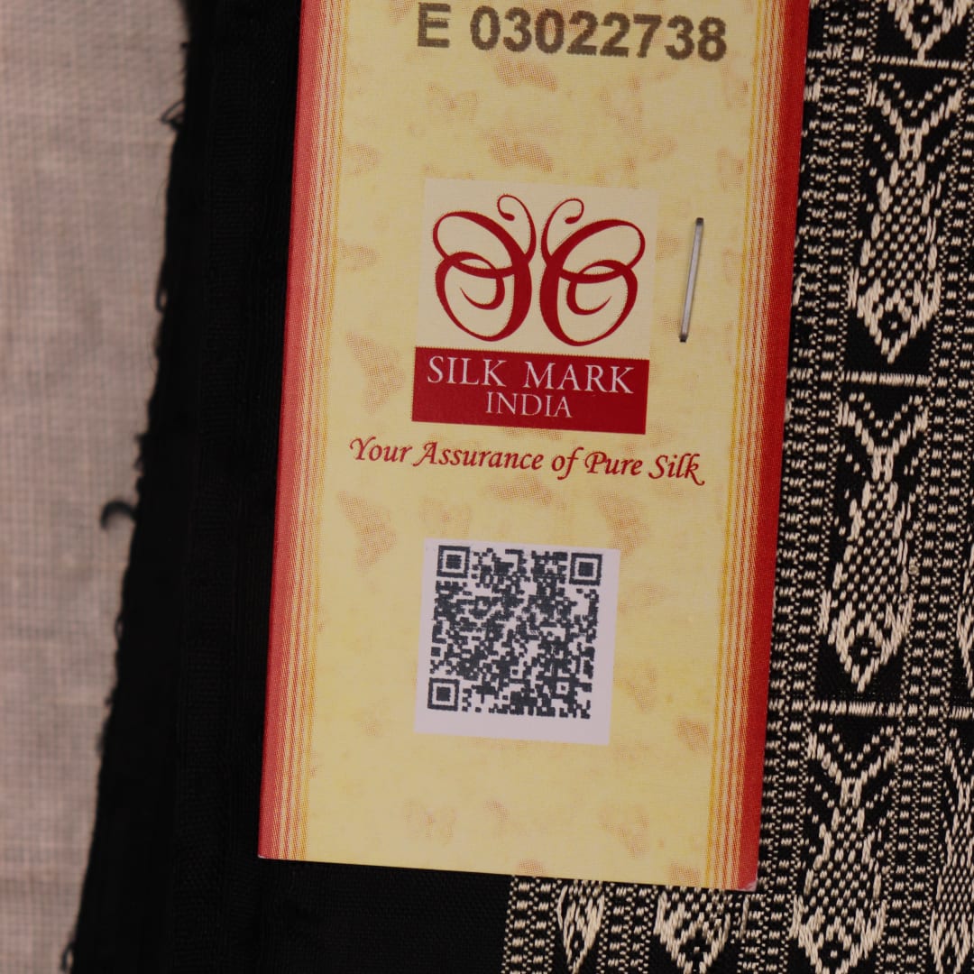 Close-up view of the smooth, lustrous texture of black silk fabric with a Pasapalli pattern in the Sambalpuri style