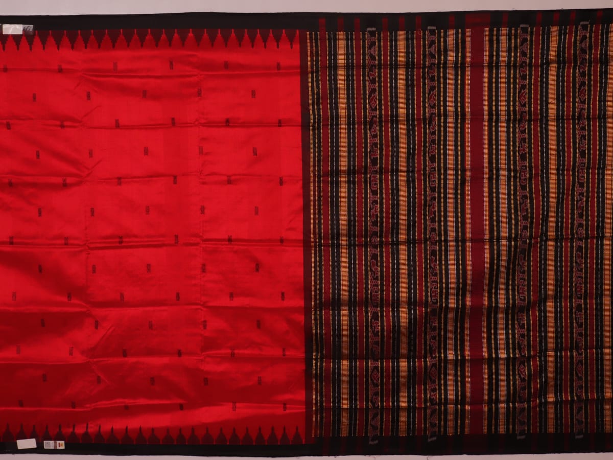 Textured close-up of red and black Sambalpuri Silk Saree fabric, highlighting the woven butta pattern.