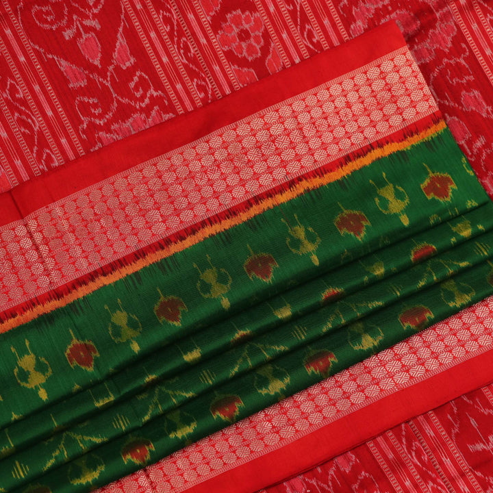 Close-up of green and orange silk Sambalpuri saree fabric with intricate motif patterns