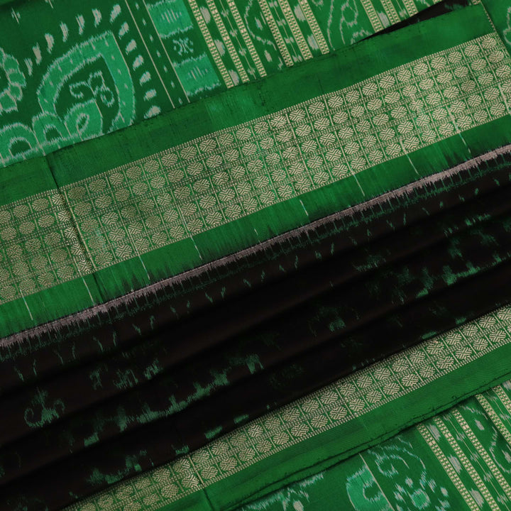 Close-up showcase of the exquisite silk texture with intricate motifs in a black and green Sambalpuri saree.