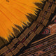Model showcasing yellow Khandua silk saree with black butta pattern.
