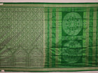 Close-up view of the intricate silk fabric texture of a green Sambalpuri silk saree with traditional motifs.