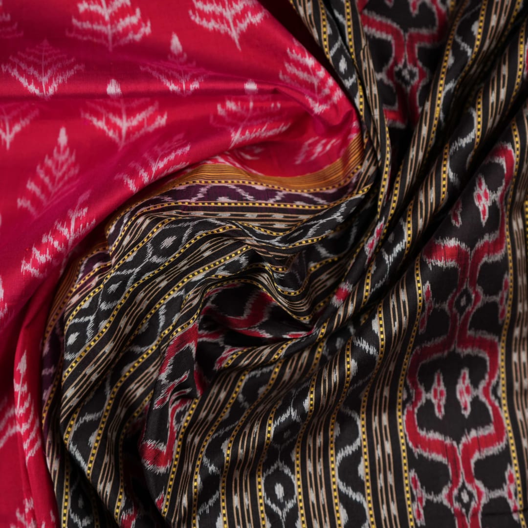 Close-up of the luxurious, handloom silk texture of the red Sambalpuri saree, showing the weave.