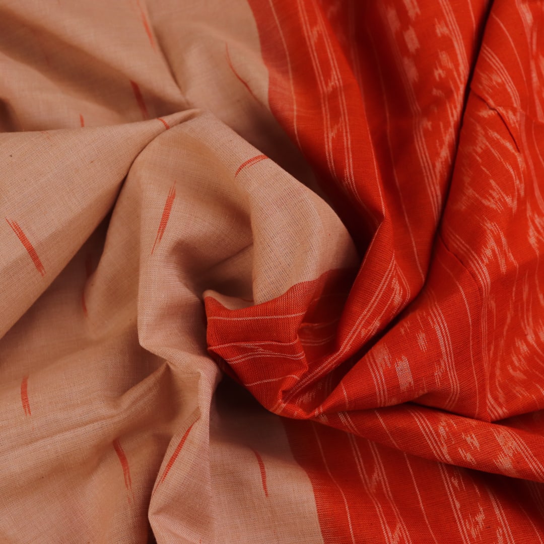 Cream and orange Sambalpuri cotton saree draped, showcasing traditional motifs and handloom texture.