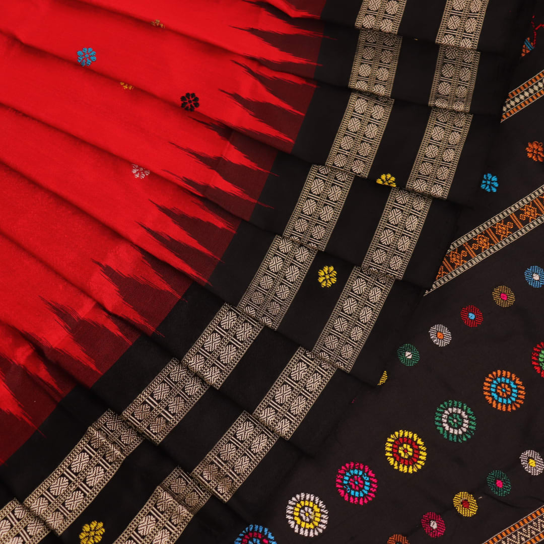 Close-up view of the soft and lustrous silk fabric texture of a Dolabedi red and black handloom saree with a butta pattern.