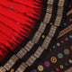 Close-up view of the soft and lustrous silk fabric texture of a Dolabedi red and black handloom saree with a butta pattern.