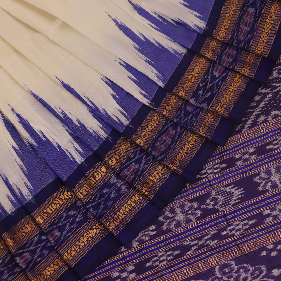 Woman elegantly draped in a white and blue Khandua silk saree with butta pattern.