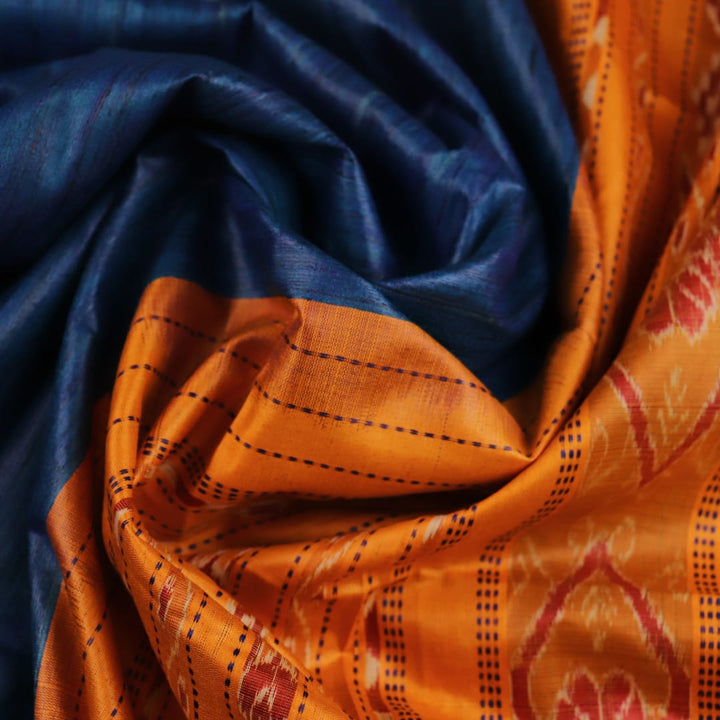 Close-up showcasing the intricate blue tussar silk fabric with a plain pattern and yellow accent hues.