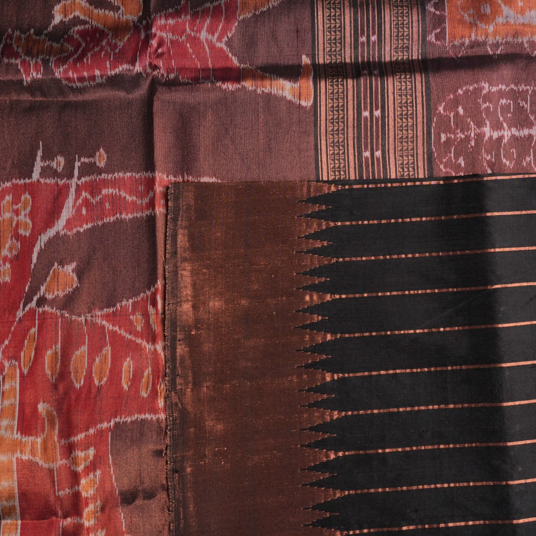 Extreme close-up showing the rich black and brown Sambalpuri Silk fabric texture and intricate handloom weave.