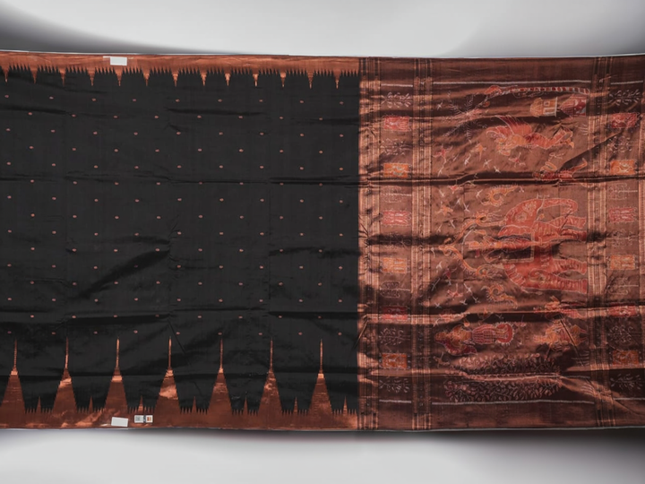 Extreme close-up showing the rich black and brown Sambalpuri Silk fabric texture and intricate handloom weave.