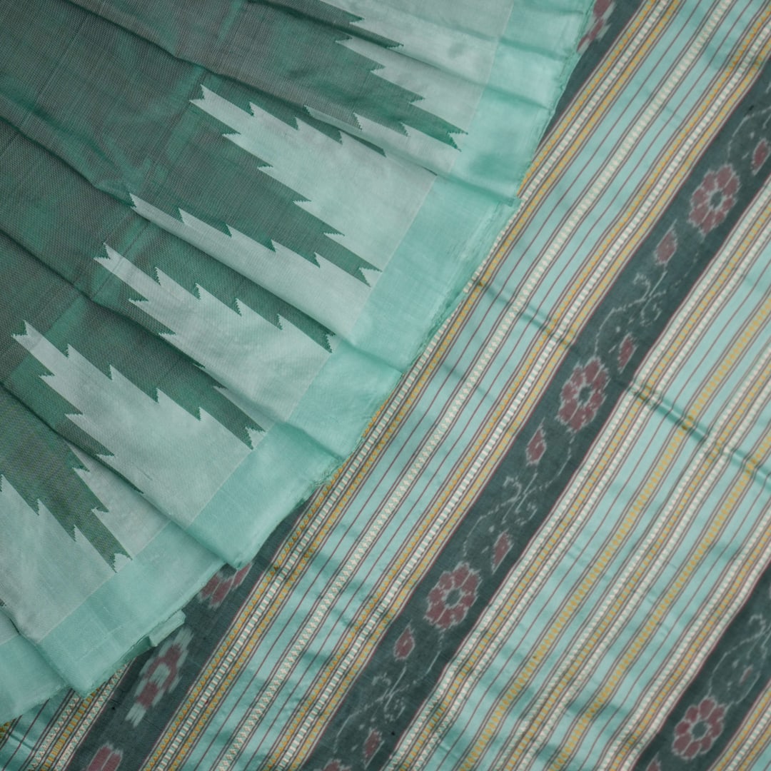 Extreme close-up of the green Sambalpuri silk fabric, revealing its luxurious texture and fine handloom weave.