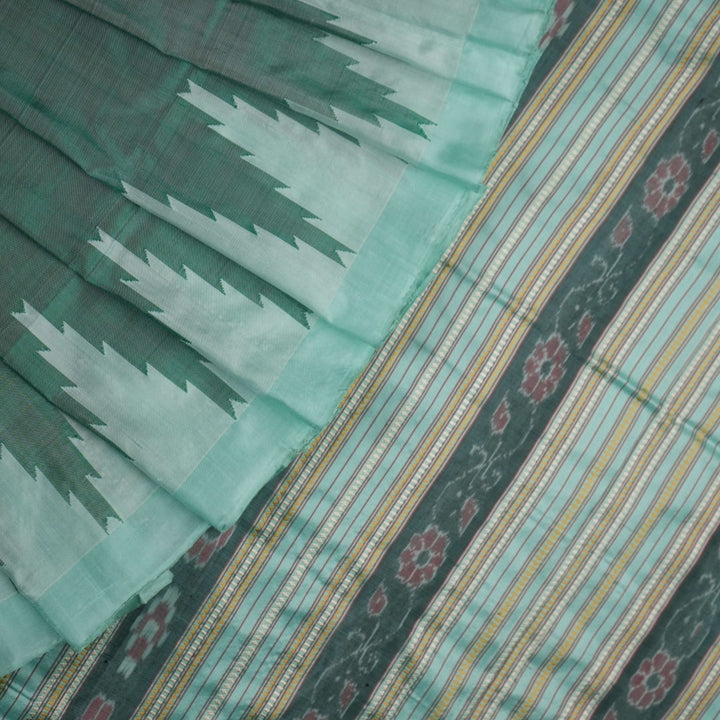 Extreme close-up of the green Sambalpuri silk fabric, revealing its luxurious texture and fine handloom weave.
