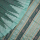 Extreme close-up of the green Sambalpuri silk fabric, revealing its luxurious texture and fine handloom weave.