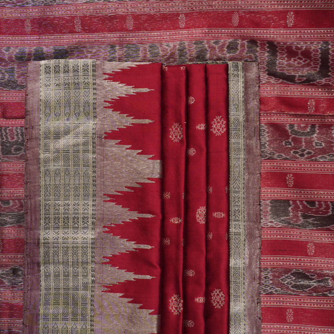 Extreme close-up revealing the rich texture and intricate handloom weave of the maroon and grey Sambalpuri silk fabric.