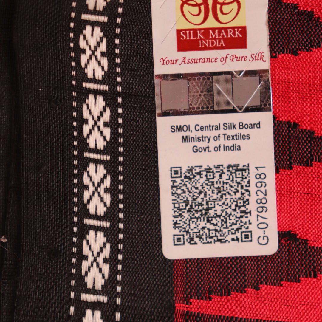 Close-up of the red and black plain silk fabric texture of a Berhampuri saree