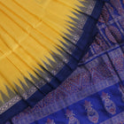 Textured close-up of yellow Bomkai silk saree fabric with blue butta pattern.