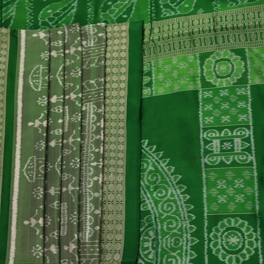 Close-up view of the intricate silk fabric texture of a green Sambalpuri silk saree with traditional motifs.