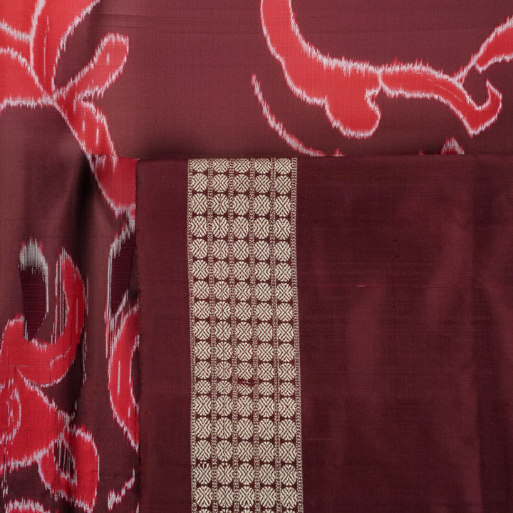 Extreme close-up of the lustrous rust Sambalpuri silk fabric, showing its fine weave and subtle motif texture.